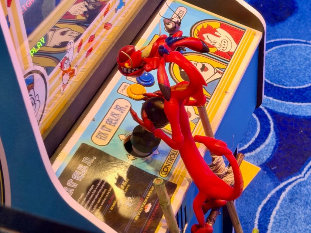 Mushu diante da pequena máquina de arcade de Fix-It Felix Jr.